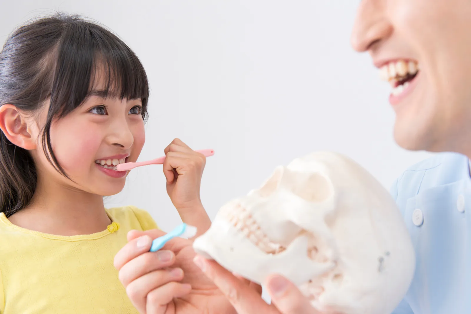 歯科医が模型を使って説明し、お子さんが笑顔で聞いている様子